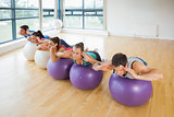 Fitness class exercising on fitness balls in a row