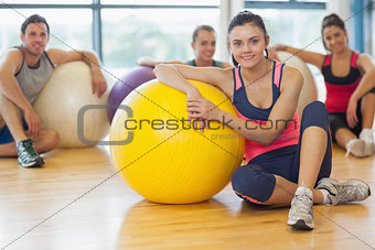 Instructor and fitness class with exercise balls at gym