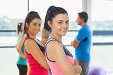 Instructor with fitness class in background in fitness studio