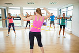 Fitness class and instructor swinging hula hoops at the waist