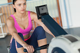 Woman working out on row machine in fitness studio