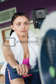 Woman working out on row machine in fitness studio