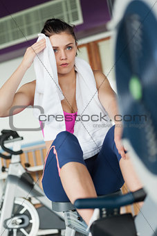 Tired young woman working out on row machine