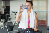 Tired woman drinking water while working out at spinning class