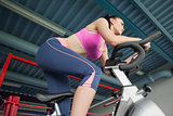 Determined young woman working out at spinning class