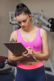 Serious female trainer with clipboard in gym