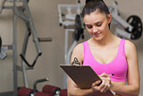 Female trainer writing on clipboard in gym