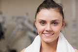 Smiling woman with towel around neck in gym