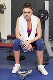 Tired and thoughtful young woman sitting in gym