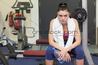 Portrait of a tired and thoughtful woman sitting in gym