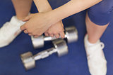 Low section of a tired woman with dumbbells in gym
