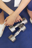 Low section of a tired woman with dumbbells in gym