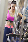 Determined woman doing exercises in gym on lat machine