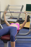 Fit woman lifting the barbell bench press in gym