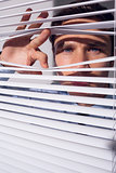 Businessman peeking through blinds