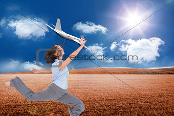 Composite image of happy businesswoman jumping while holding smartphone
