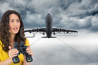 Composite image of serious young woman holding binoculars
