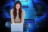 Composite image of brunette sitting using laptop