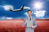 Composite image of businessman holding a clipboard