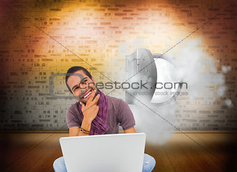 Composite image of man sitting on floor using laptop and smiling