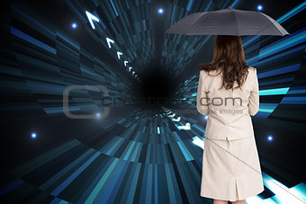 Composite image of rear view of businesswoman holding umbrella