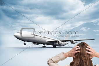 Composite image of young businesswoman with hands on head standing back to camera