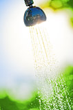 flowing water from a watering can shower in the sun
