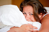 young woman hugging a pillow in bed