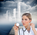 Composite image of serious nurse listening with stethoscope