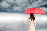 Composite image of businesswoman holding umbrella