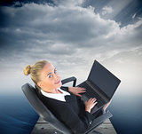 Composite image of businesswoman sitting on swivel chair with la