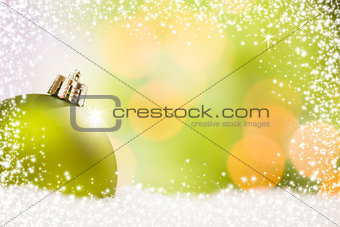 Green Christmas Ornament on Snow Over an Abstract Background