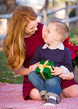 Young Boy Holding Christmas Gift with His Mom in Park