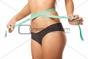 Young fit woman measuring her waistline
