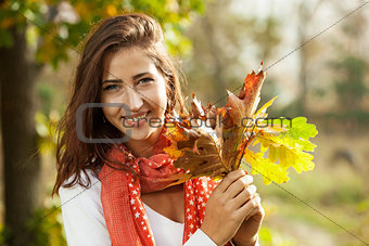 Young girl with autumn leaves in hand on sunny day