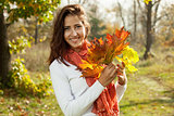 Young girl with autumn leaves in hand on sunny day