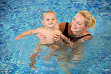 Young mother and little son having fun in a swimming pool