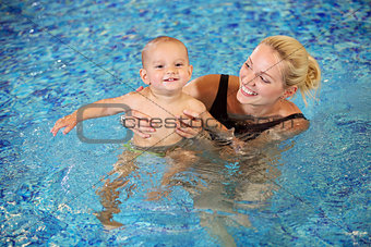 Young mother and little son having fun in a swimming pool