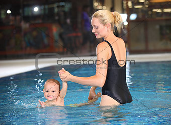 Young cheerful mother and little son in a swimming pool
