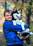 Portrait of young man holding his husky dog outdoors