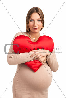 Smiling pregnant woman with heart shaped pillow over white