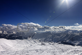 Ski slope and blue sky with sun rays