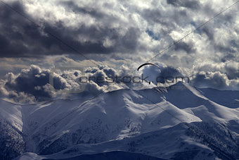 Evening mountain with clouds and silhouette of parachutist