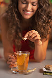 Closeup on happy young woman putting brown sugar cube into ginge