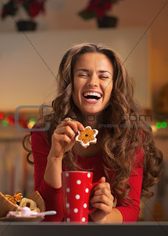 Happy young woman enjoying christmas snacks in kitchen