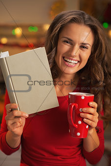 Happy young woman with book cup of hot chocolate