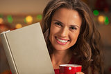 Portrait of happy young woman with book cup of hot chocolate