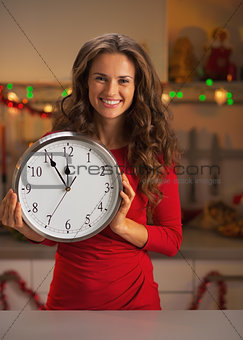 Portrait of smiling young woman holding clock in christmas decor
