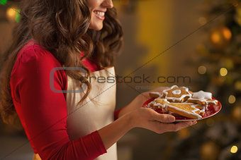 Closeup on young housewife enjoying with plate of christmas cook