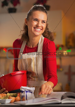 Happy young housewife preparing christmas dinner in kitchen